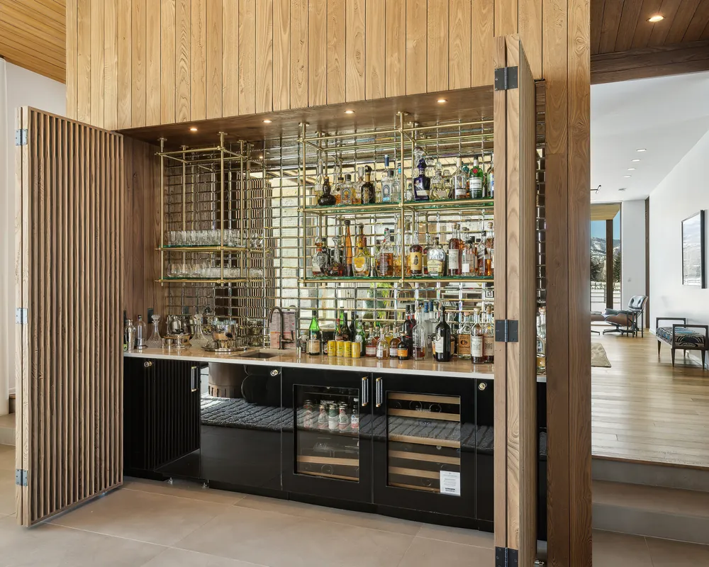 Built-in bar with brass shelving and a wine fridge in a Park City home managed by Life Elevated