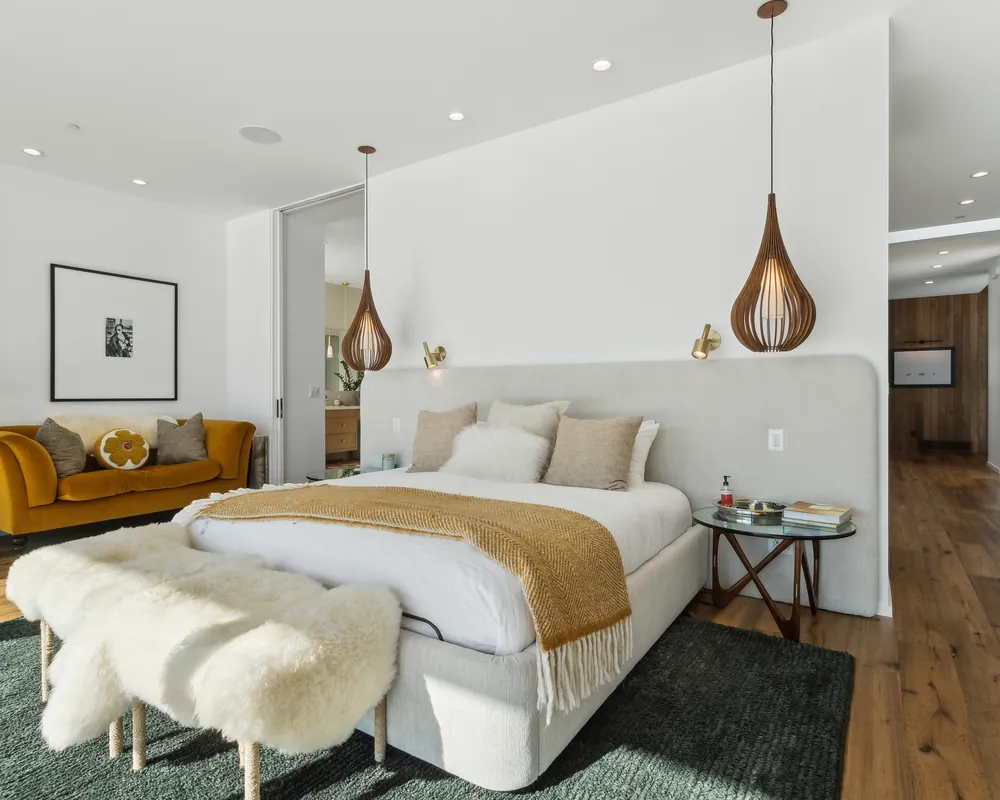 Bright primary bedroom with a sheepskin bench and a velvet sofa in a Park City home managed by Life Elevated