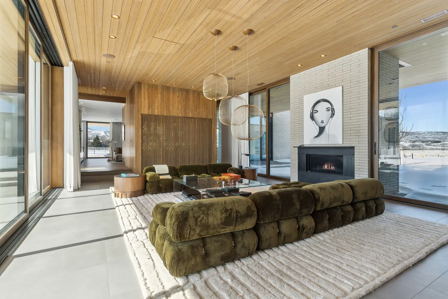 Great room with a green velvet sectional, a fireplace, and floor-to-ceiling windows in a Park City home managed by Life Elevated