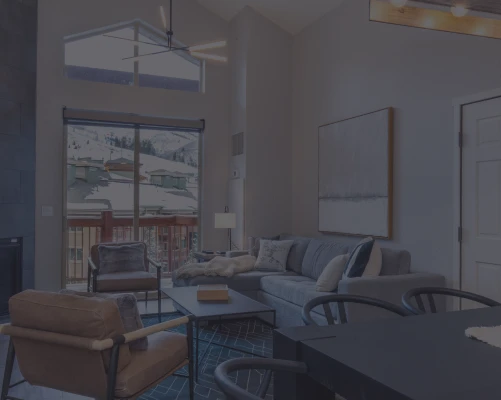 Vaulted living room with a gray sectional and a snowy mountain view in a Life Elevated vacation rental